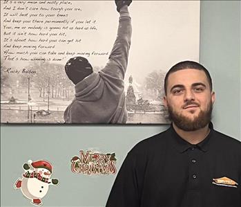 SERVPRO employee in front of wall with picture behind