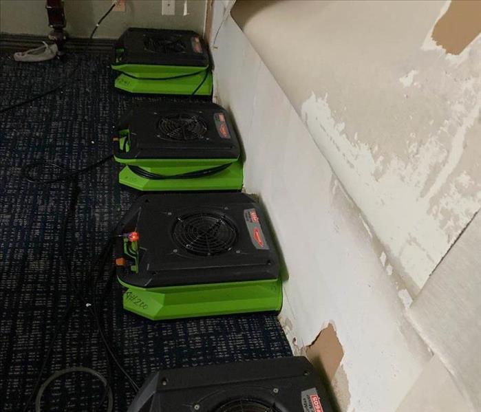 Four air movers pointed against a wall.