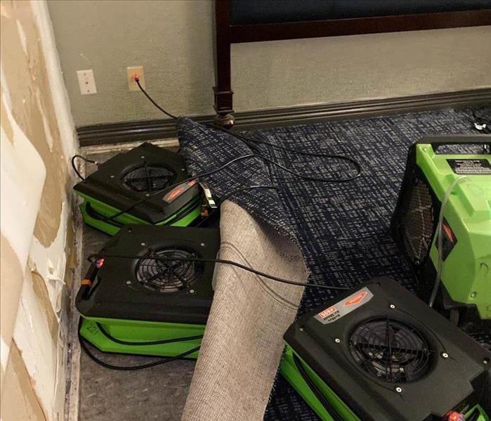Air movers drying underneath carpets.