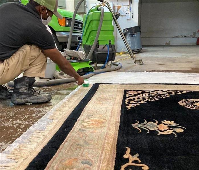 servpro employee cleaning a rug with servpro equipment